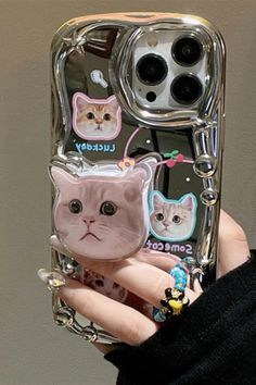 a person holding up a cell phone case with cat stickers on the front and sides