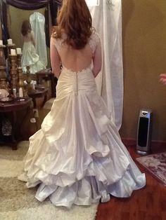 a woman in a wedding dress looking at herself in the mirror