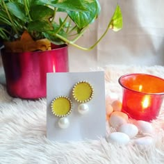 a pair of earrings sitting on top of a white rug next to a potted plant