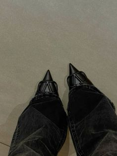 a person's feet with black shoes and jeans