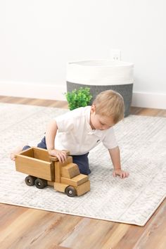 a little boy playing with a wooden toy truck