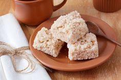 two pieces of rice krispy treats on a plate with a cup of coffee in the background