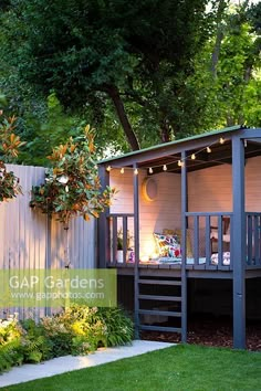 a small wooden shed with lights on the roof and stairs leading up to it's deck