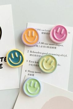 three different colored smiley face buttons sitting on top of a piece of paper next to a sign