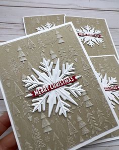 handmade christmas card with snowflakes and merry lettering on the front, two hands holding