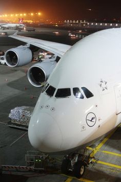 an airplane parked on the tarmac at night time with other planes in the background