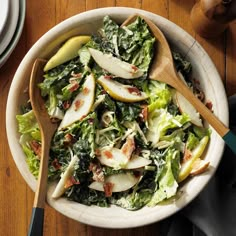 a salad with apples, bacon and lettuce in a white bowl on a wooden table