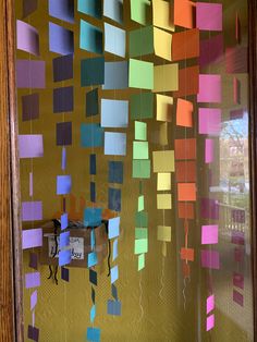 colorful sticky notes are hanging on the glass wall in front of an open door with a clock