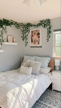 a bedroom decorated in white and grey with plants hanging on the wall above the bed