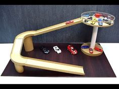 a wooden table topped with toy cars on top of a wooden shelf next to a gray wall