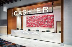 a cashier counter in front of a red painting on the wall behind it that says cashier