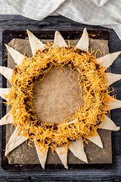 a sunflower wreath made out of tortilla shells and shredded cheese on a baking sheet