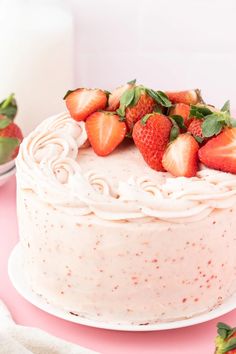 a strawberry cake with frosting and fresh strawberries on top, ready to be eaten