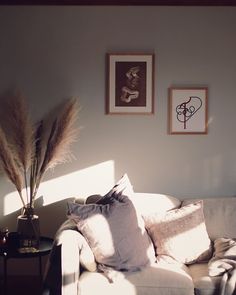 a white couch sitting in a living room next to a table with a vase on it