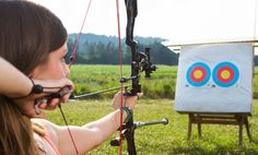 a woman is aiming an arrow at the target