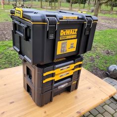 two black and yellow tool boxes sitting on top of a wooden table in a park