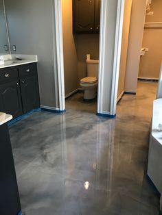 an empty bathroom with grey floors and white fixtures on the walls, along with black cabinets