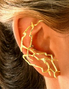 a close up of a person wearing gold ear cuffs with two different designs on them