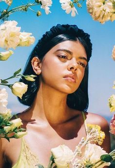 a woman standing in front of flowers with her eyes closed and one hand on her face