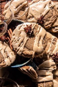 cookies with icing and star anise sit on a plate next to other cookies