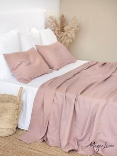 a bed with two pillows on top of it next to a basket filled with flowers