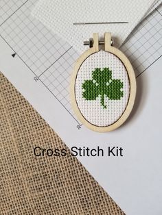 a cross stitch shamrock is hanging on a piece of fabric