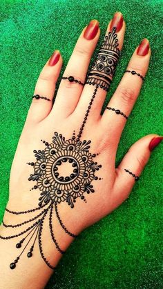 a woman's hand with henna tattoos on it and some beads around the wrist