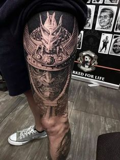 a man's leg with tattoos on it and an image of a demon in the middle