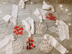 six glass christmas ornaments with red and white lettering on them, sitting on a wooden table