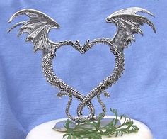 a silver dragon sculpture sitting on top of a white cake covered in frosting and greenery