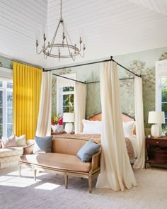 a bedroom with four poster bed and yellow drapes