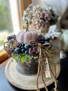 an arrangement of flowers and berries in a vase on a table next to a window