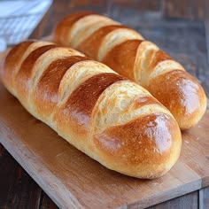 two loaves of bread sitting on top of a wooden cutting board
