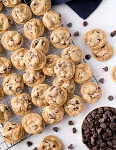 cookies and chocolate chips on a cooling rack next to a bowl of chocolate chip cookies