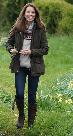 a woman standing in the woods wearing a brown jacket