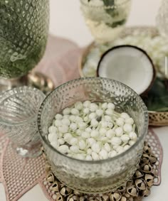 there is a glass bowl filled with small white flowers on the table next to other dishes