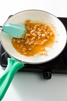 a pan with some food cooking on top of an electric stove burner next to a green spatula