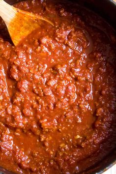 a wooden spoon in a pot filled with chili