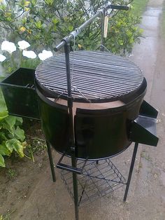 an outdoor bbq grill sitting on the side of a road next to some bushes