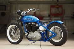 a blue and white motorcycle parked in a garage next to another bike with the words top fuel ii written on it