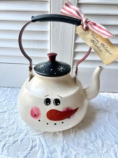 a tea pot with a face painted on it and a tag hanging from the handle