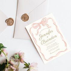 the wedding stationery is laid out next to some flowers and two wax stampers