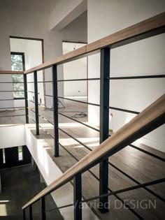 an empty room with stairs and railings in the foreground, light shining through windows