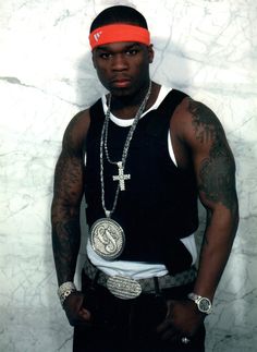 a man with tattoos and a red headband standing in front of a marble wall