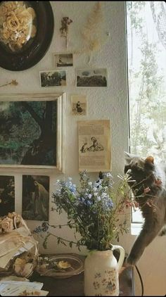 a cat standing on top of a table next to a vase filled with flowers