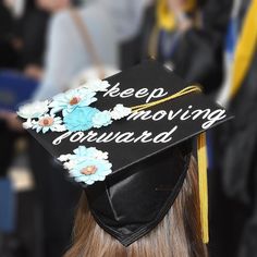 a graduation cap that says keep moving forward with flowers on the side and words written in white