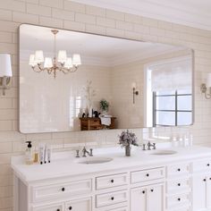 a white bathroom with two sinks and a large mirror above the double sink countertop