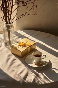 Morning sunlight illuminating a beautifully presented cup of tea and a wrapped gift on a table. Early Morning Sun