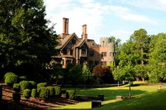 an old house in the middle of a park with trees and bushes on both sides