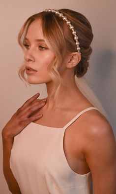 a woman in a white dress wearing a headband with pearls on it's side